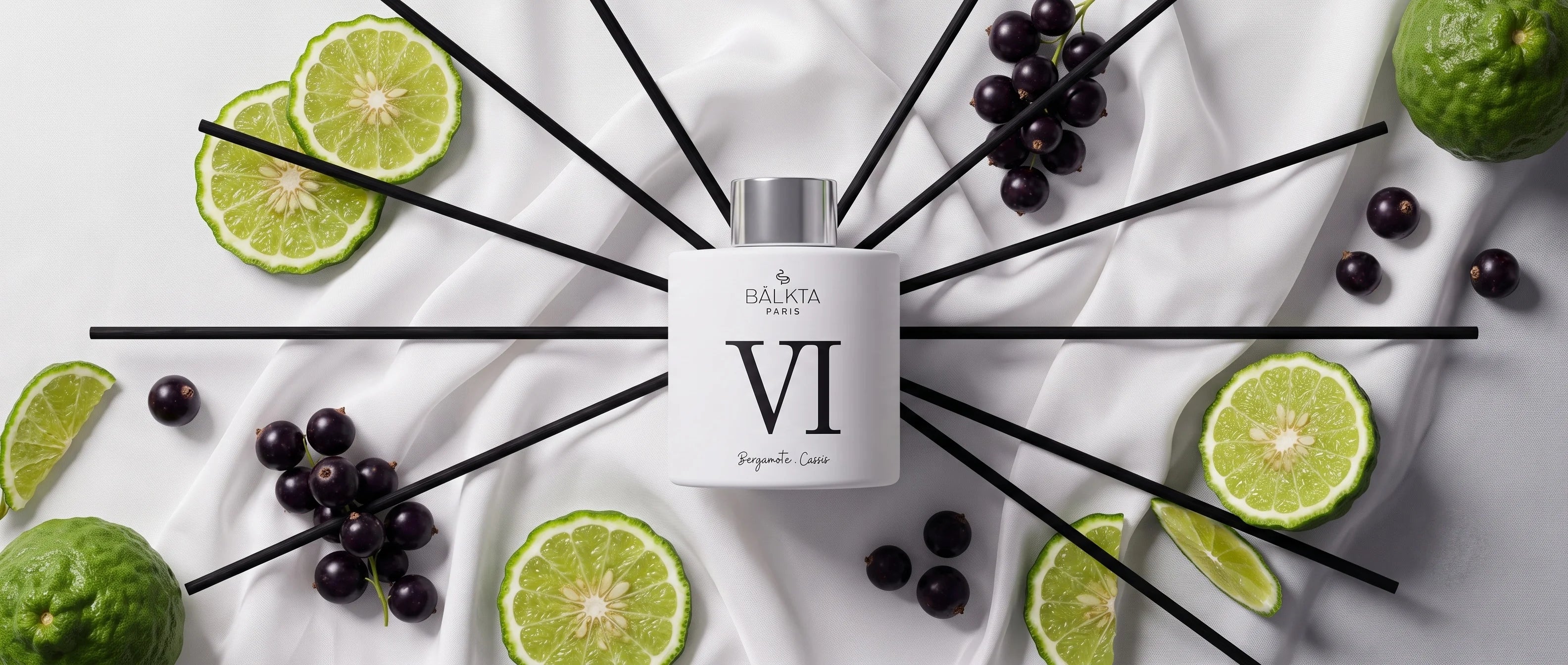 Diffuseur de parfum d'intérieur à bâtonnets Bälkta Paris numéro VI, senteur Bergamote et Cassis. Prise de vue de dessus montrant le flacon blanc entouré de tranches de bergamote fraîches et de baies de cassis sur un élégant drapé blanc.